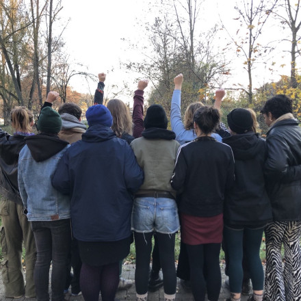 Eine Gruppe Menschen steht mit dem Rücken zur Kamera und reckt die Fäuste in die Höhe